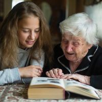 Known Memory Care | Senior looking at a book with granddaughter